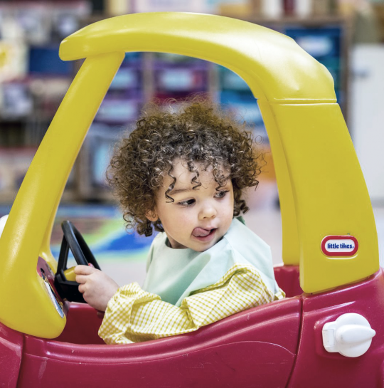 Little nursery boy sitting in play car