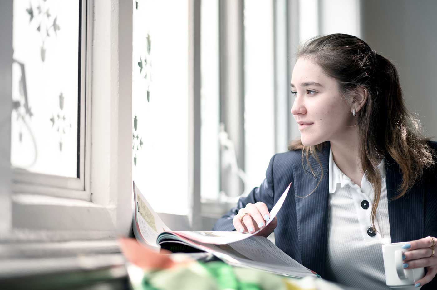 Female student sitting at a window with a book