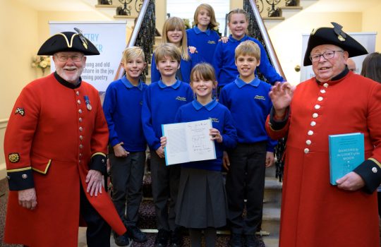 Students and Royal Chelsea Pensioners holding a certificate